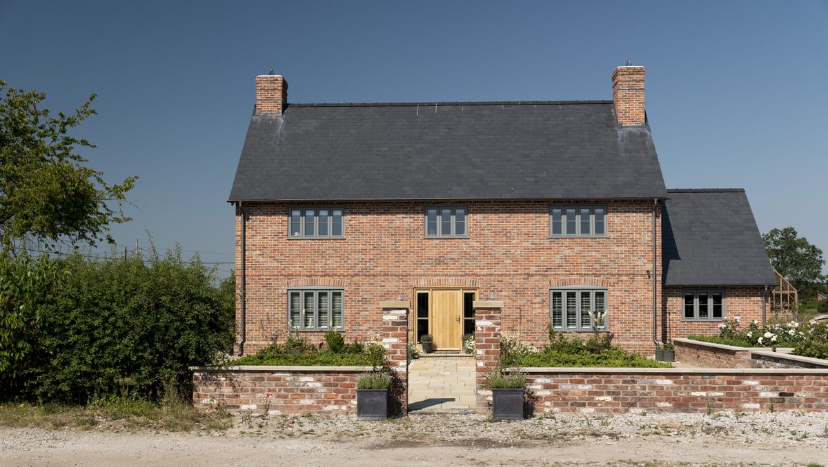 Red-brick detached UK house with slate roof and neat guttering